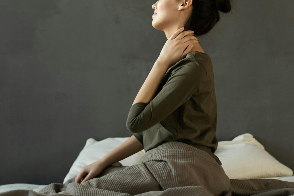 Woman rubbing back of their neck in pain