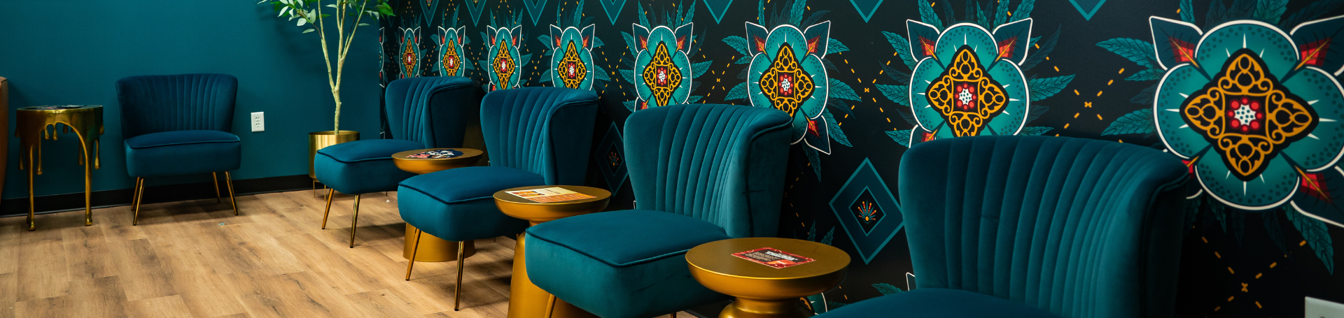 four teal chairs lined against wall with eclectic wallpaper in waiting area