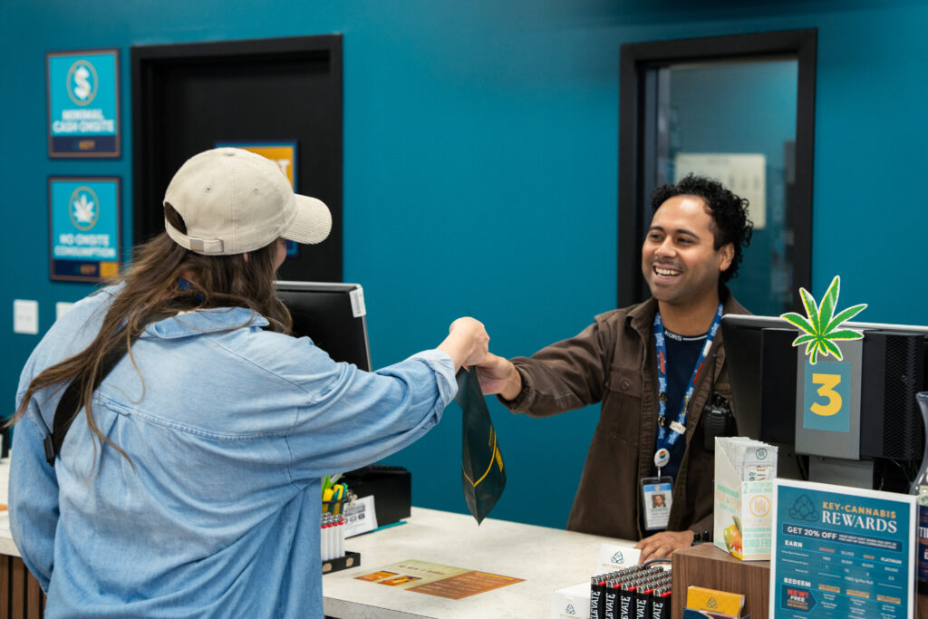 Woman taking purchase from Budtender at Key Cannabis