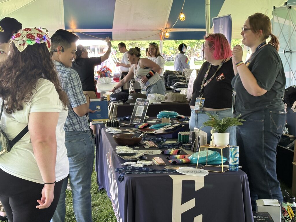 People standing in front and behind a table in a festival tent