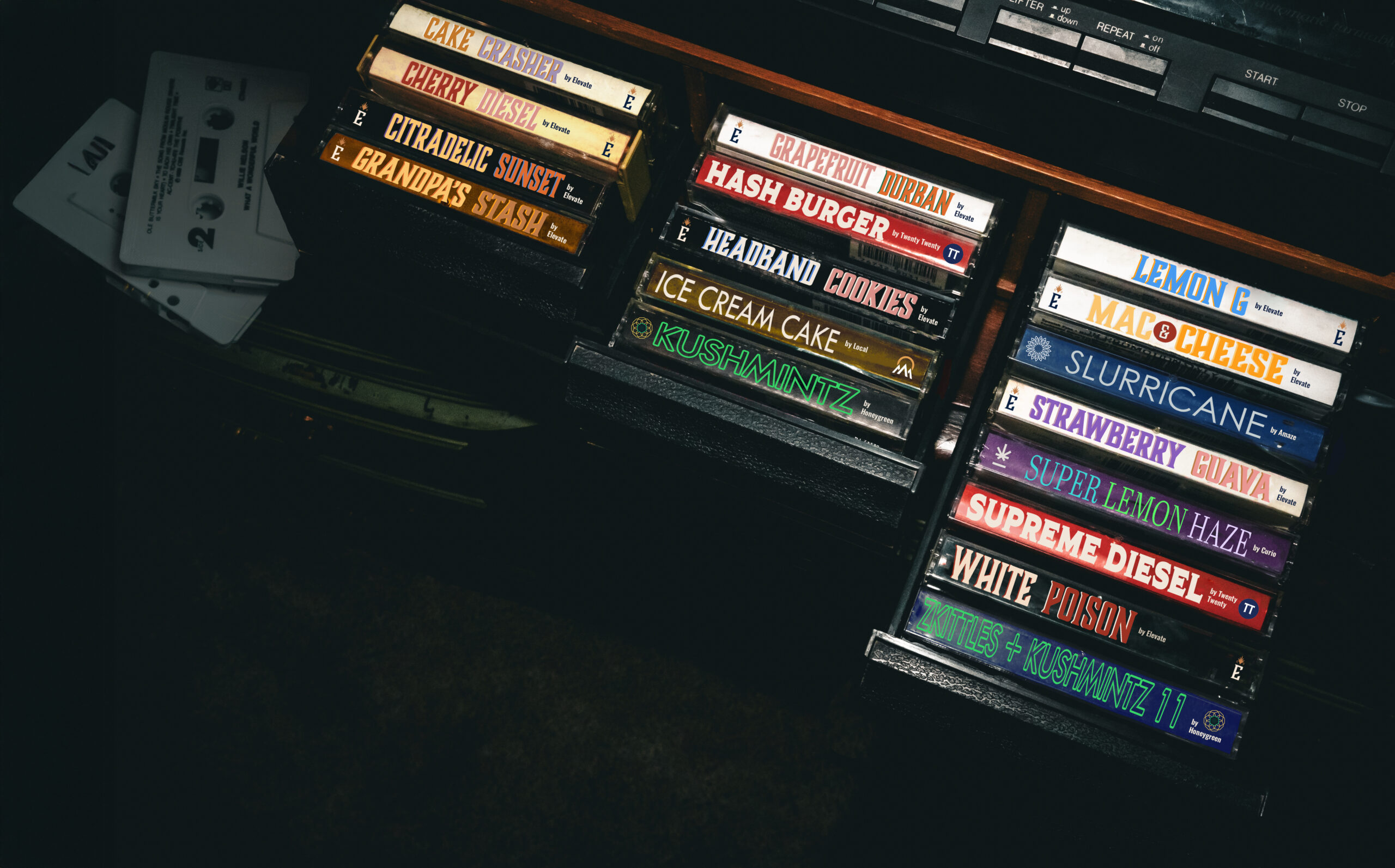 Colorful tapes in a tape deck with cannabis strain names on the sides.