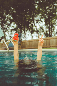 Woman's arm sticking out of a pool holding a Keef Soda