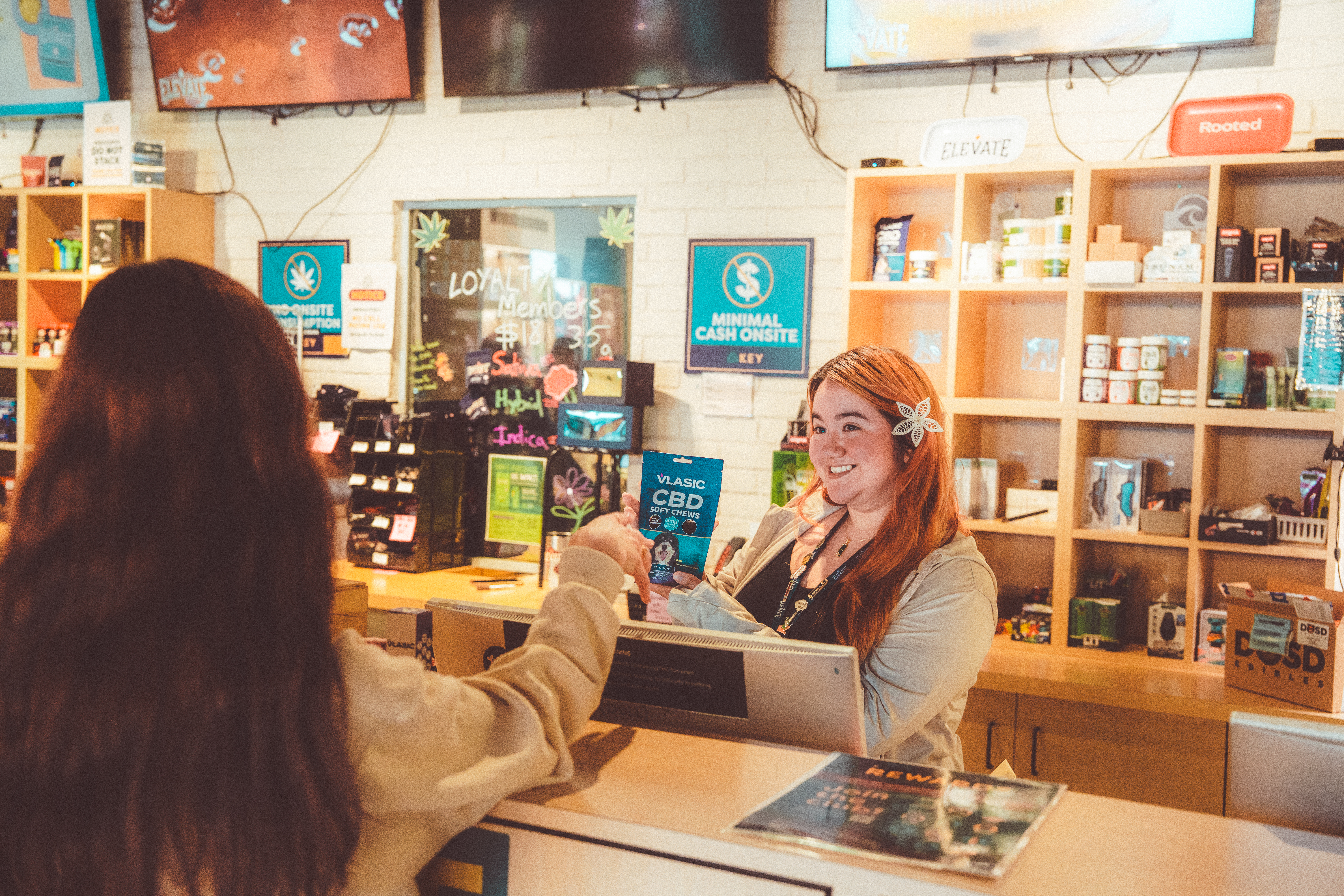 Woman behind a dispensary counter handing product to a customer